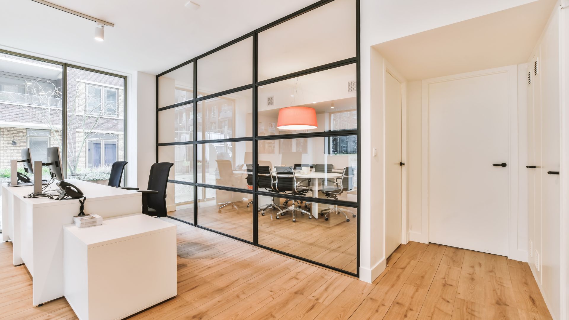 A room with a desk, chairs, and a large window