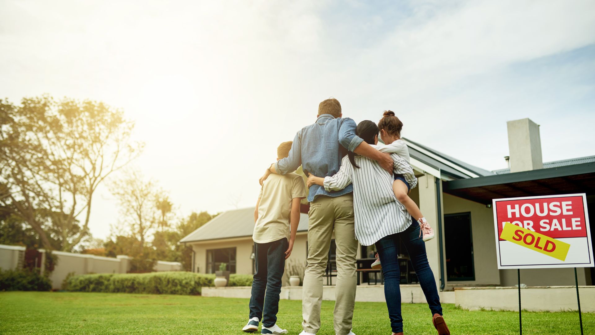 A group of people standing in front of a house for sale